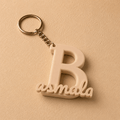 Personalized initial B keychain featuring the custom name Basmala in elegant script, 3D printed in matte beige PLA with a durable metal key ring. A unique custom gift for birthdays, anniversaries, graduations, and everyday use.