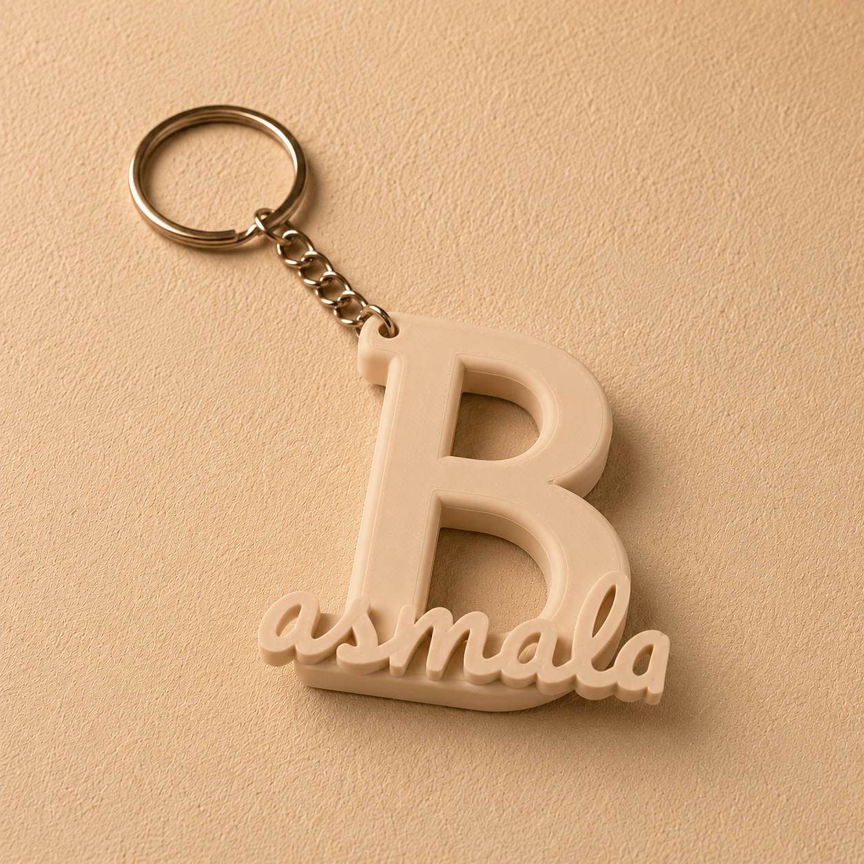 Personalized initial B keychain featuring the custom name Basmala in elegant script, 3D printed in matte beige PLA with a durable metal key ring. A unique custom gift for birthdays, anniversaries, graduations, and everyday use.